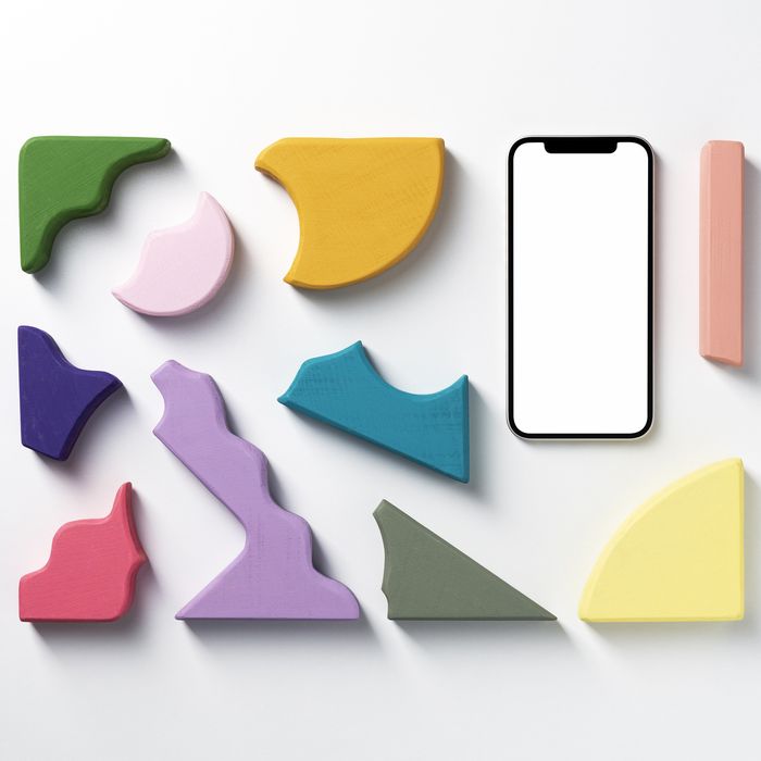 Blank screen smart phone mockup, template with clipping path. Colorful wooden stacking toy, puzzle, toy blocks. Pastel colored geometric wooden shapes flat lay on white background.