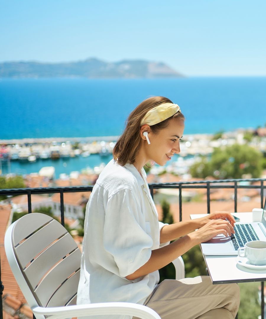 Young,Woman,Using,Laptop,Computer,At,Cafe,Balcony,Of,Resort