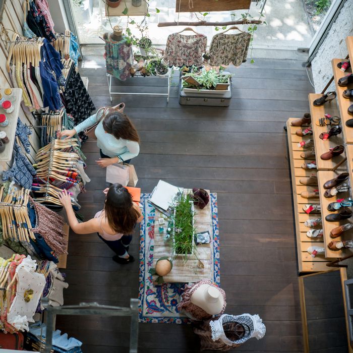 Happy couple of women shopping at a clothing store - consumerism concepts