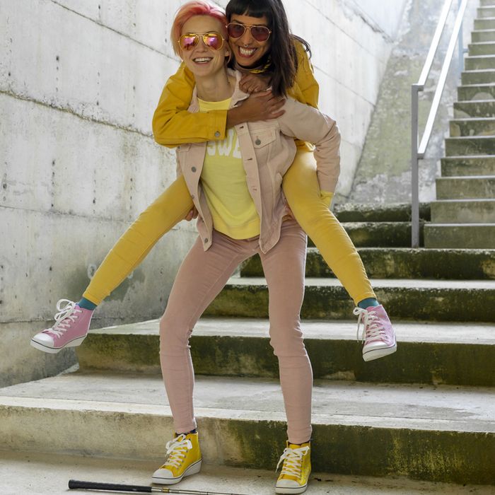 Two alternative friends having fun, wearing yellow and pink jeans clothes.