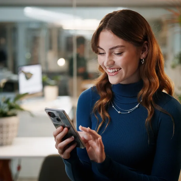 Cellphone, business and happy woman in office at night for communication, contact or funny email. Female employee, tech and scroll for feedback, social media joke or finished deadline or overtime.AI personalization