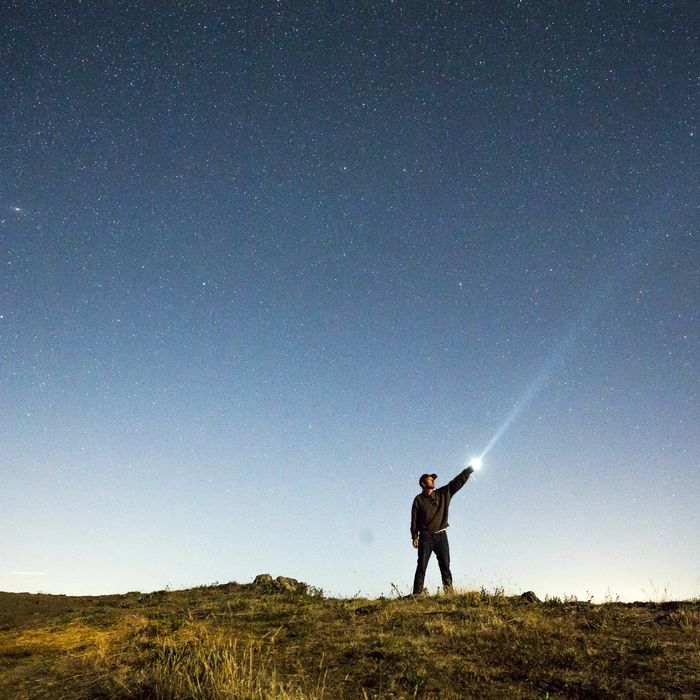 Caucasian man pointing flashlight at night sky