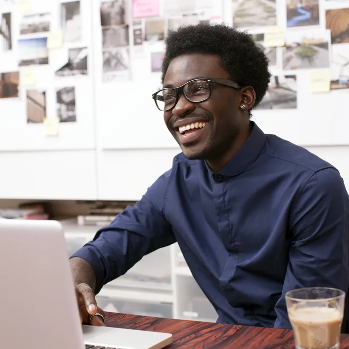 A young man working at his desk in a creative office environment - corporate business - laptop computer