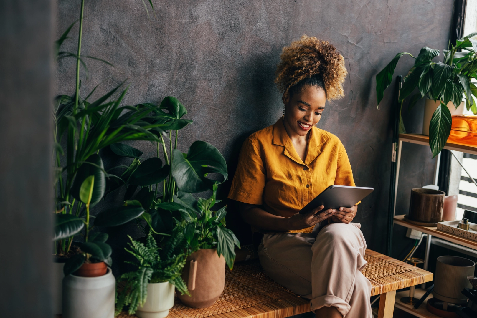 A smiling African-American entrepreneur working on her tablet while running her florist shop.