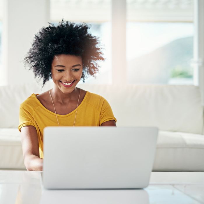 Cropped shot of an attractive young woman using her laptop while chilling at home