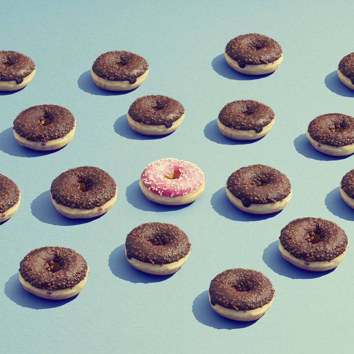 One pink donuts stands out amongst chocolate donuts