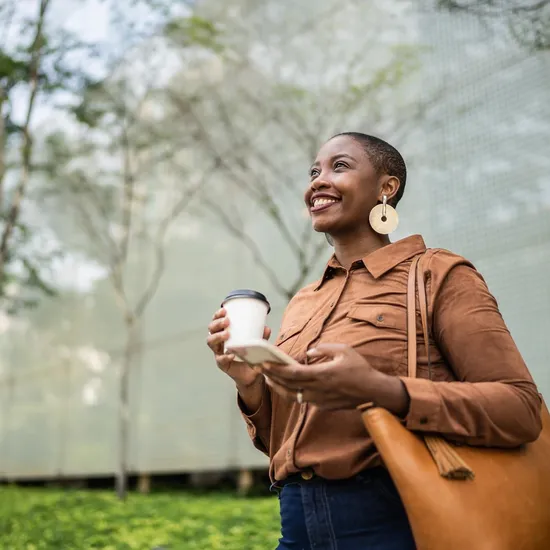Business woman holding smartphone and looking away outdoors
