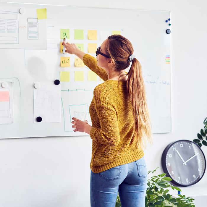 Back view of female web designer working on whiteboard in office