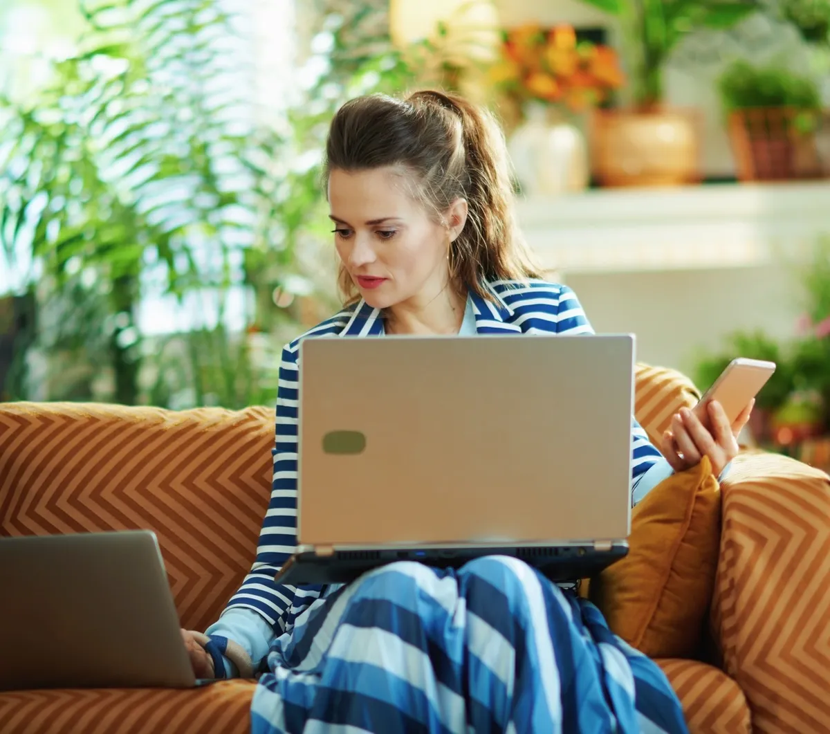 housewife in modern house in sunny day using devices 