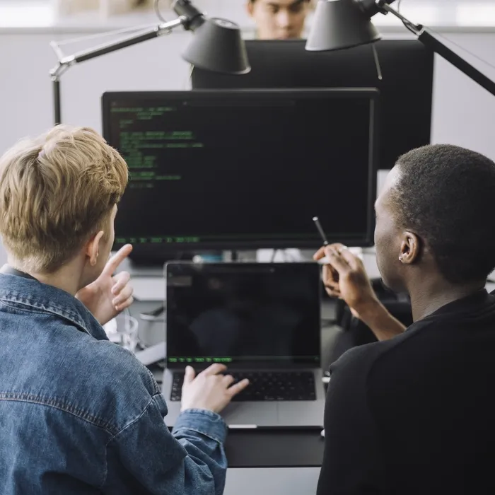 Male computer programmers discussing over codes at desk in office