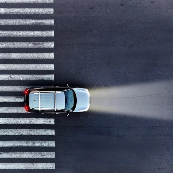 Aerial.,A,Car,With,Its,Headlights,On,Drives,Over,A