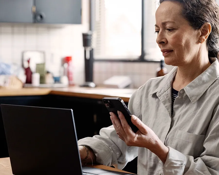 A woman using her phone and laptop