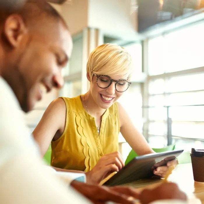 Team of young casual business people collaborating on an online project using a digital touchpad tablet computer in a bright modern office space. Serie with light flares