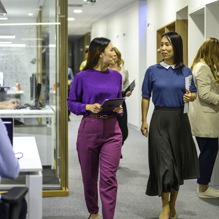 Mature businesswomen doing discussion while walking at corridor in office.Colorful Human
