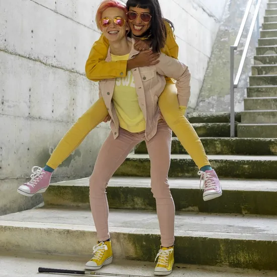 Two alternative friends having fun, wearing yellow and pink jeans clothes.