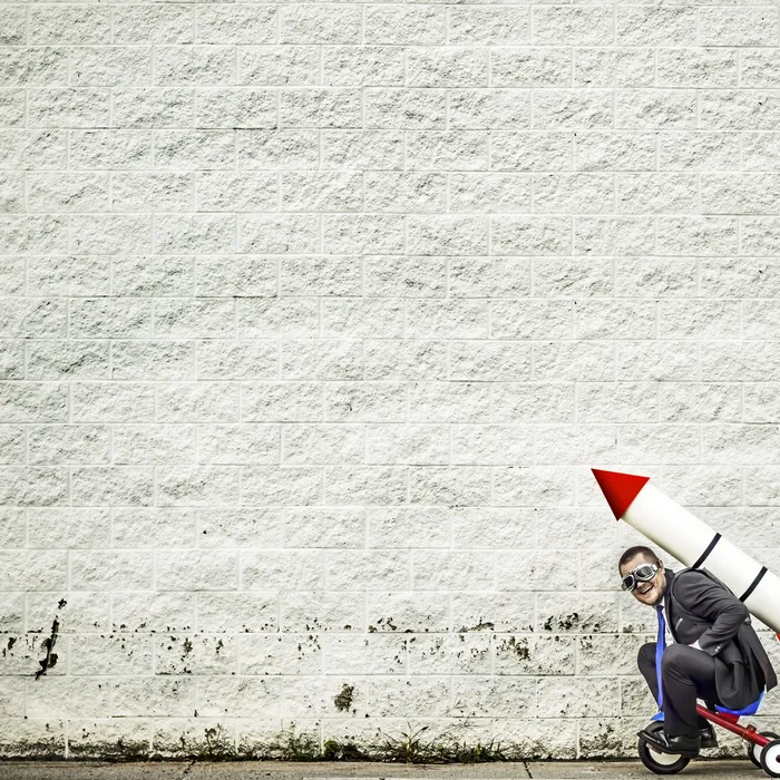 Businessman riding a tricycle and getting help from the rocket strapped to his back :-)