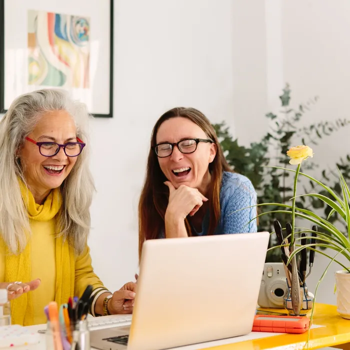 Two women looking at a laptop screen and laughing