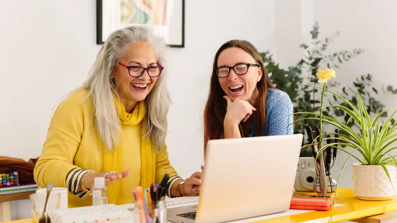Two women looking at a laptop screen and laughing