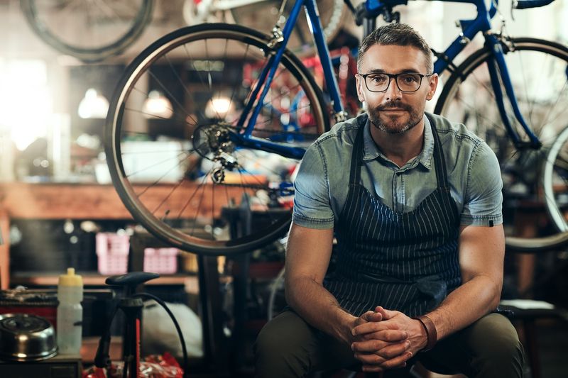 Portrait,,Mechanic,And,Man,In,Bicycle,Shop,,Store,And,Cycling