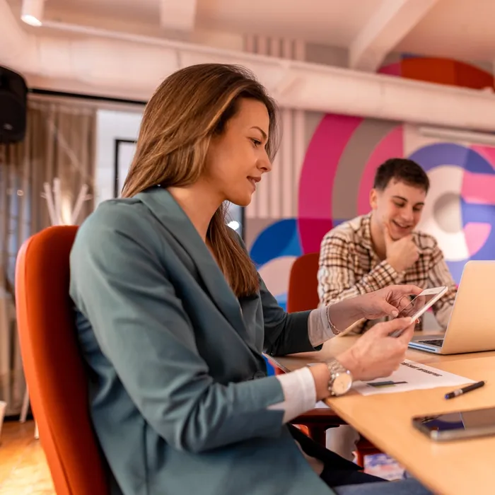 Group of young businesspeople collaborating in a modern office, discussing a new project while using laptops and smartphones, showcasing teamwork and innovative ideasColorful Human