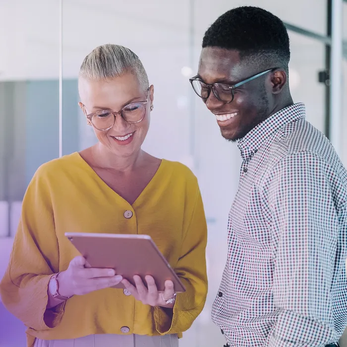 Two colleagues reviewing something together on a tablet in a modern office