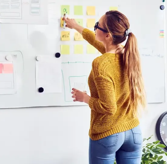Back view of female web designer working on whiteboard in office