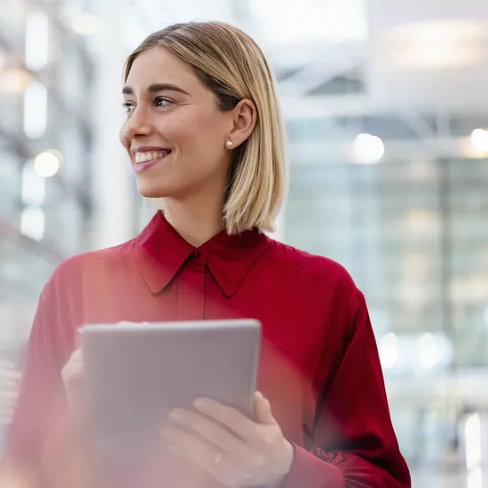 Smiling young businesswoman wearing red shirt using tabletColorful Human