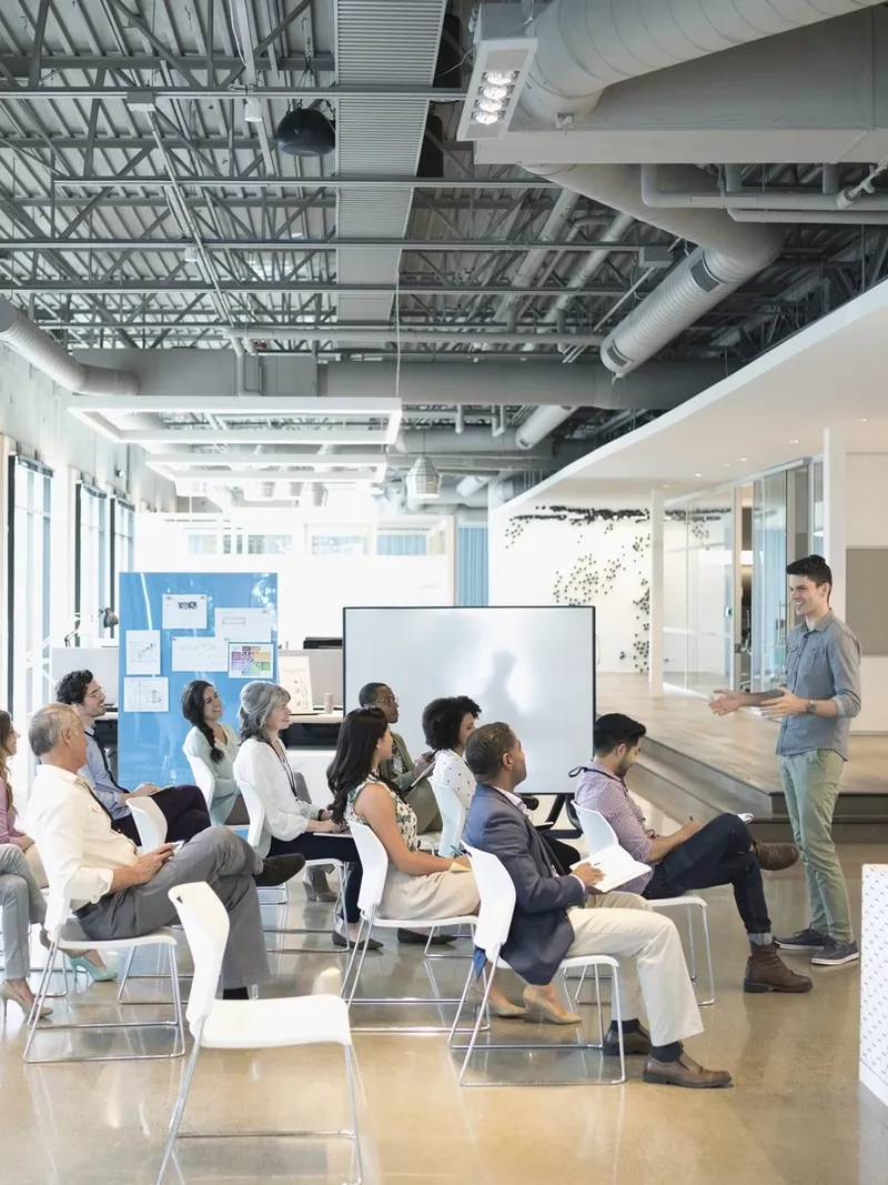 Conference audience listening to businessman leading presentation in office