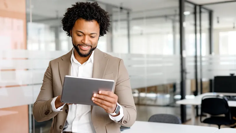 African-American young businessman looking at his tablet with an expression of pleasant surprise. This shot perfect for conveying concepts like real-time data analysis, business agility, e-commerce