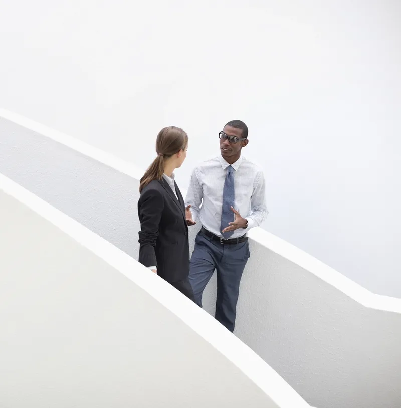 Businessman and businesswoman talking on modern staircase
