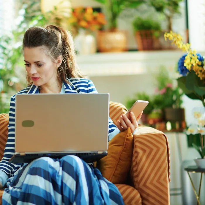 housewife in modern house in sunny day using devices 