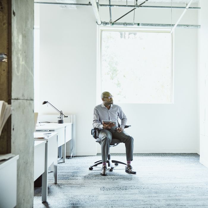 Businessman reviewing project plans on office wall while working on digital tablet