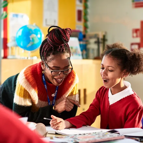 Elementary school teacher marking girl's work, success, achievement, understanding