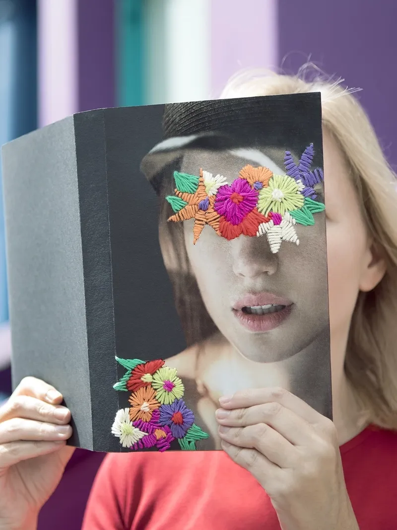 Woman covering face with book, reading poetry in the city