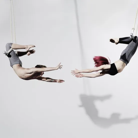 Circus artists in Trapeze, Photographed on white, with shadow projected on the wall
