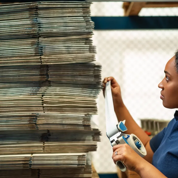 Female warehouse worker labeling the boxes. Woman in uniform working in distribution warehouse plant.Colorful Human
