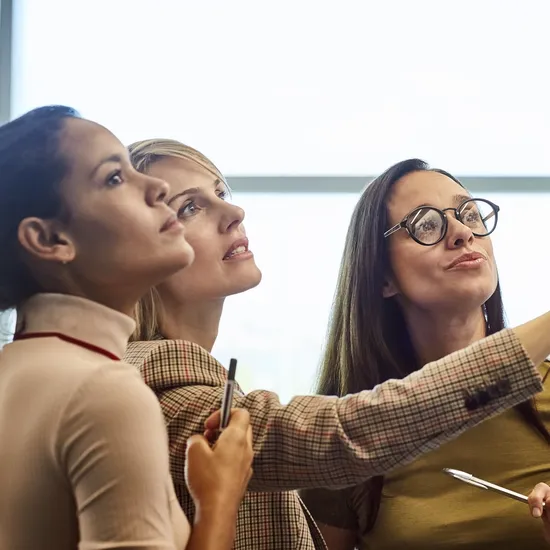 Businesswomen looking at fabric samples on presentation board. Confident female colleagues are working in textile factory. They are wearing smart casuals in office.