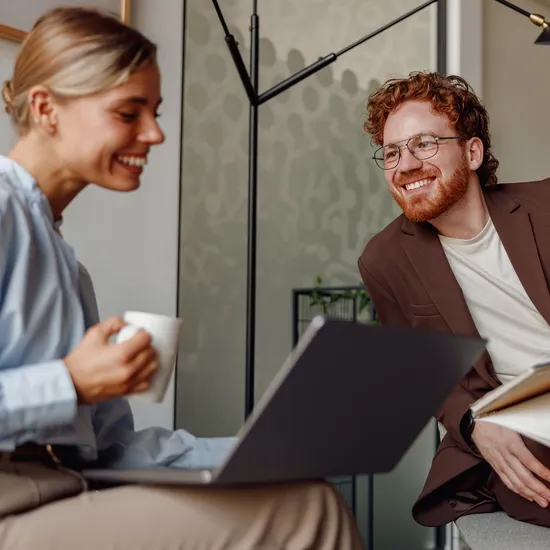 In a stylish and modern office, a woman and a man collaborate with focus on a laptop, showcasing true teamwork 