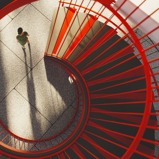 Overhead view from the top of a red staircase in a modern office building. All objects in the scene are 3DColorful Human
