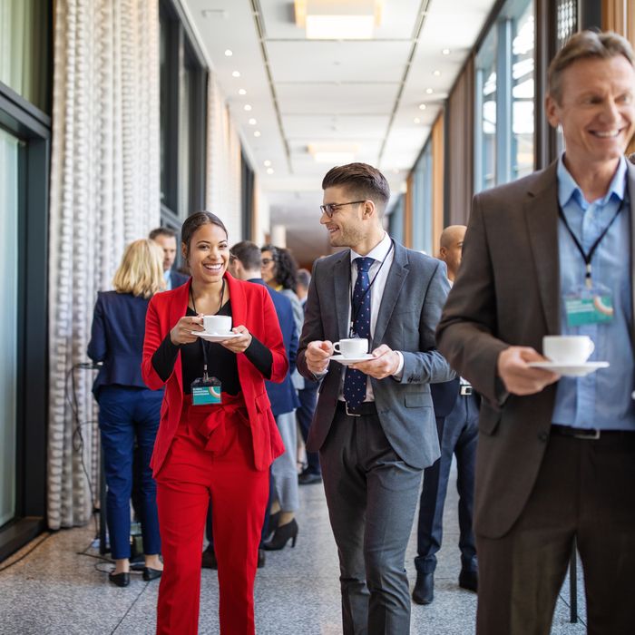 Businessman and businesswoman walking together and talking during coffee break. Business professionals walking in corridor with cup of coffee in hotel.Colorful Human