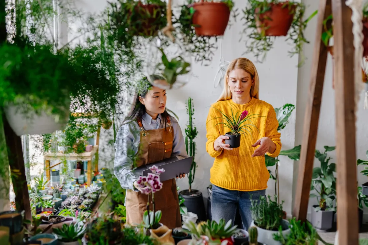Sustainable,Greenery,Consult.,Female,Asian,Shopkeeper,With,Notebook,Amid,Lush