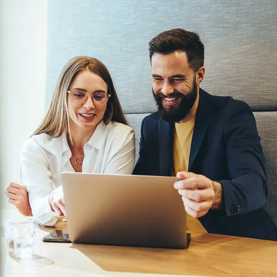 Two business professionals smiling at a laptop screen