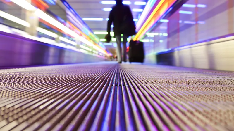 Man walks down the people mover in an airport;