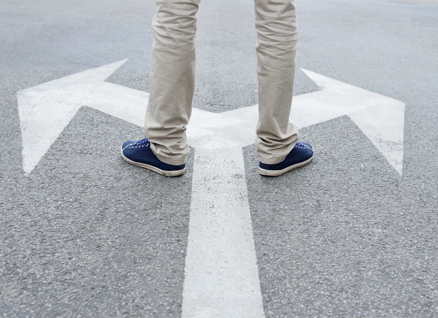Man standing on arrows painted on asphalt.