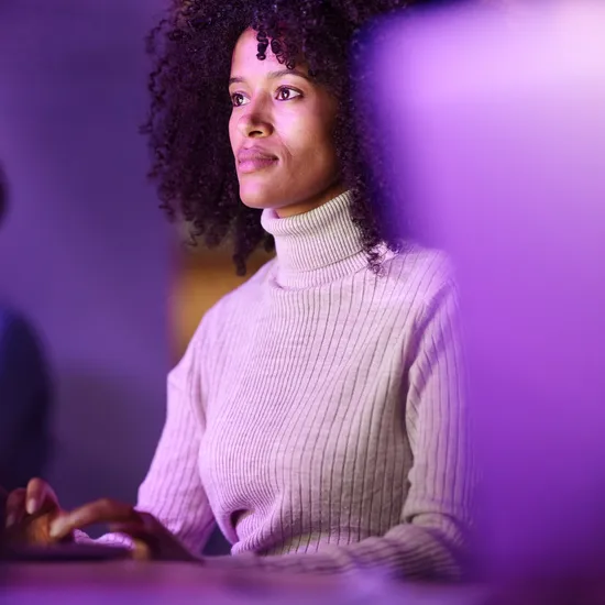 African American female graphic designer working on laptop while coding a language on desktop PC in the office.Colorful Human