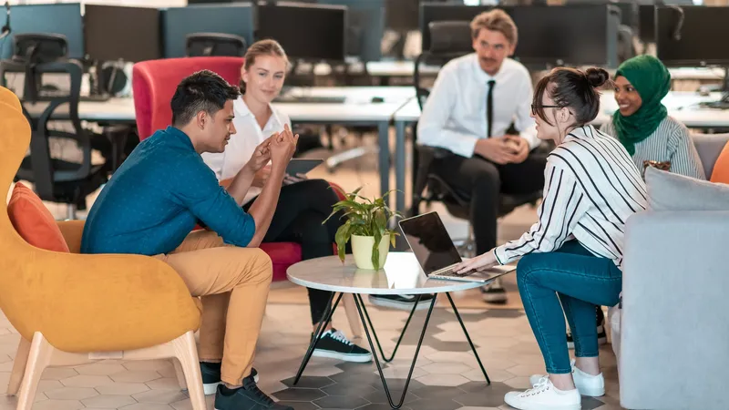 Multiethnic startup business team having brainstorming in relaxation area of modern office interior working on laptop and tablet computer. High-quality photo