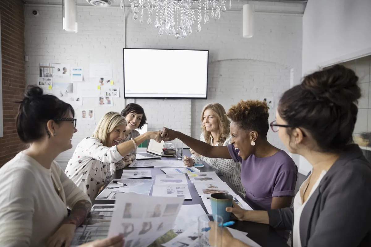 Female designers fist bumping in conference room meeting