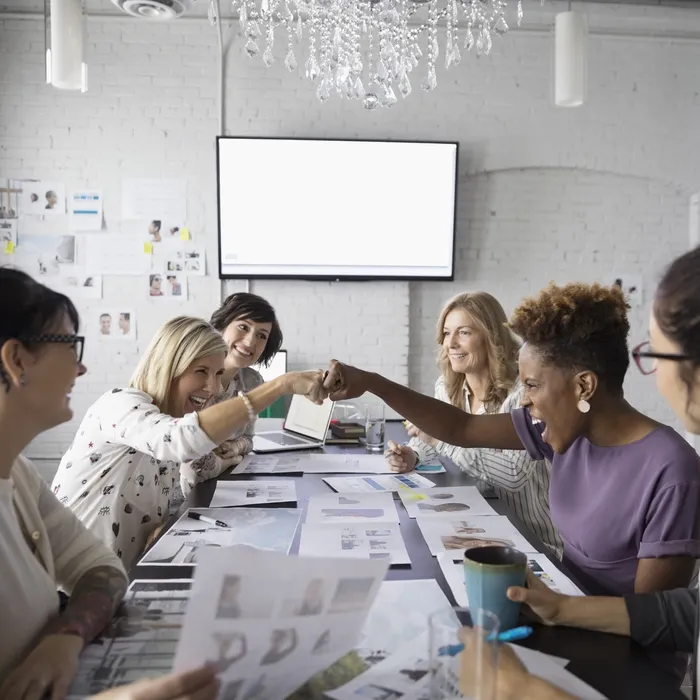 Female designers fist bumping in conference room meeting