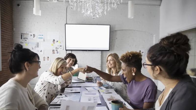 Female designers fist bumping in conference room meeting