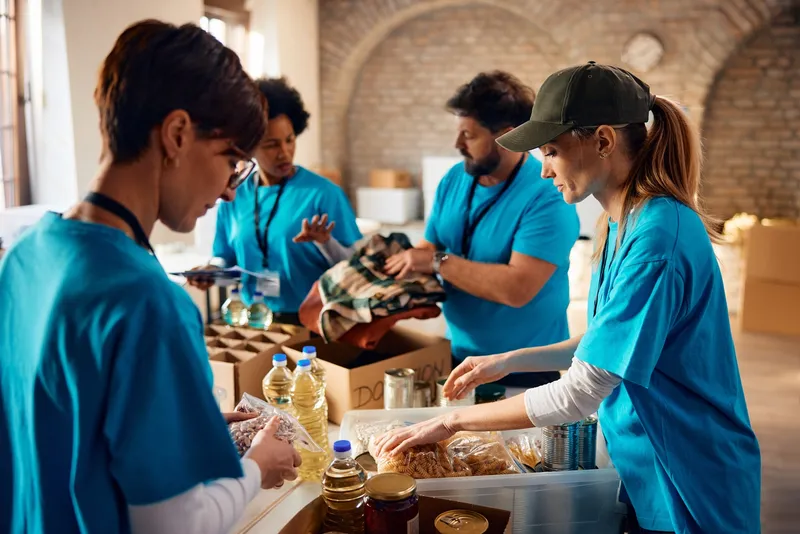 Multiracial,Group,Of,Volunteers,Packing,Groceries,At,Community,Food,Bank.